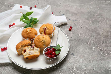 Plate with tasty cranberry muffins on grunge backgroundの写真素材