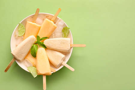 Plate with tasty melon popsicles on color background