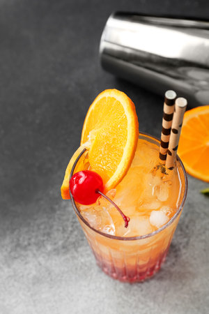 Glass of tasty Tequila Sunrise cocktail on gray backgroundの写真素材
