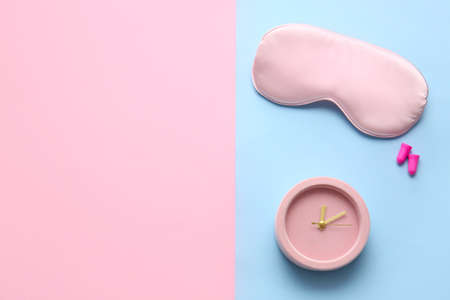Sleep mask, earplugs and alarm clock on color backgroundの写真素材