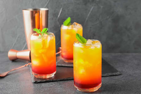 Glasses of tasty Tequila Sunrise cocktail on dark backgroundの写真素材