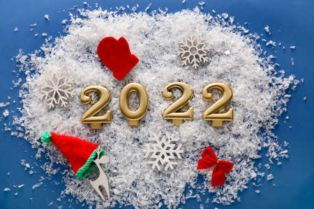Christmas composition with figure 2022 and snow on blue background
