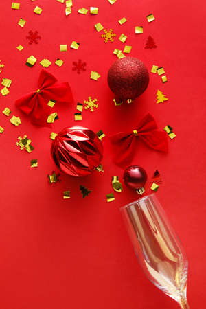 Glass with Christmas decor and confetti on red backgroundの写真素材
