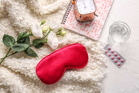 Sleep mask, pills, alarm clock and plaid on light backgroundの写真素材