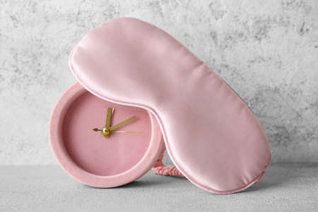 Stylish sleep mask and alarm clock on light backgroundの写真素材