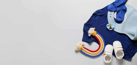 Set of baby clothes with silicone bib, pacifier and toy on light backgroundの写真素材