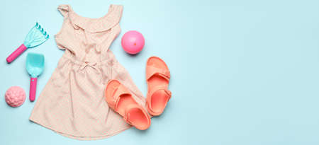 Baby's dress and beach accessories on blue background with space for textの写真素材