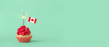 Delicious cupcake with flag of Canada and sparkler on turquoise background with space for textの写真素材