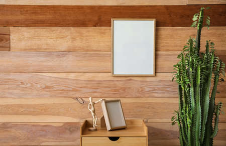 Green cactus, table with frame and mannequin near wooden wall