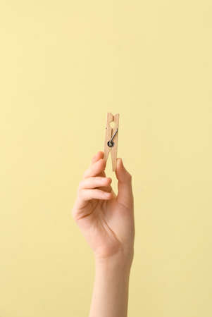 Woman holding clothespin on yellow backgroundの写真素材