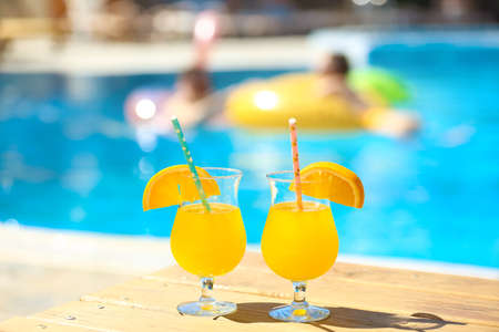 Glasses of cocktails on table near swimming poolの写真素材