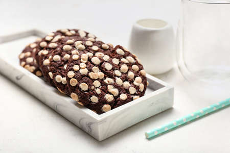 Board of tasty cookies with white chocolate chips on light background