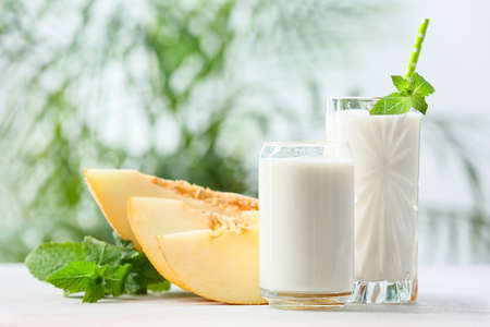 Glasses of tasty melon milkshake on tableの写真素材