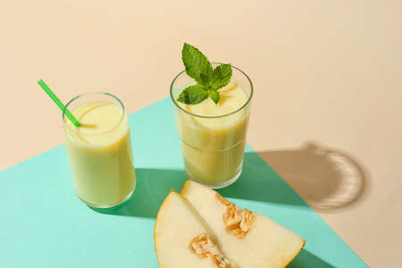 Glasses of tasty melon milkshake on color backgroundの写真素材