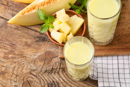 Glasses of tasty melon milkshake on wooden background, closeupの写真素材