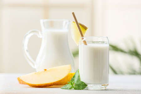 Glass and jug of tasty melon milkshake on tableの写真素材