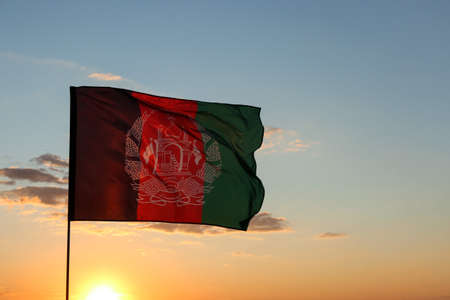 Waving Afghanistan flag against blue sky at sunsetの写真素材