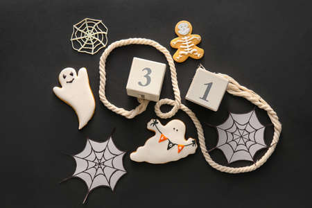 Tasty cookies for Halloween celebration with decor on dark background