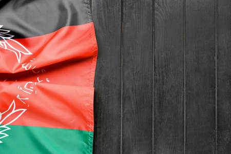 Flag of Afghanistan on dark wooden background