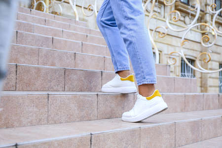 Woman going up modern stairs outdoors, closeup