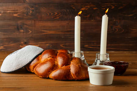 Traditional challah bread with glowing candles and Jewish cap on wooden background. Shabbat Shalomの写真素材