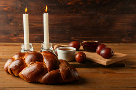 Traditional challah bread with glowing candles on wooden background. Shabbat Shalomの写真素材