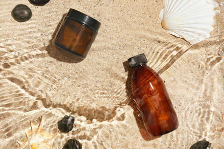 Cosmetic products and spa stones in water on sand