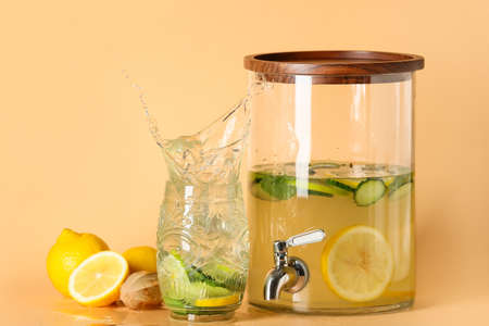 Jar and glass of tasty lemonade with splash on color background