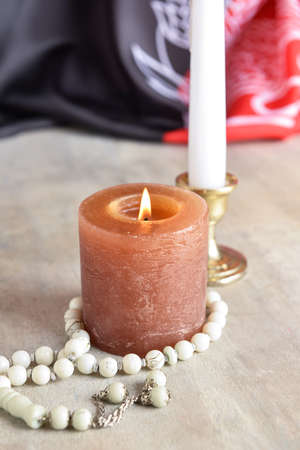 Burning candle, tasbih and flag of Afghanistan on table