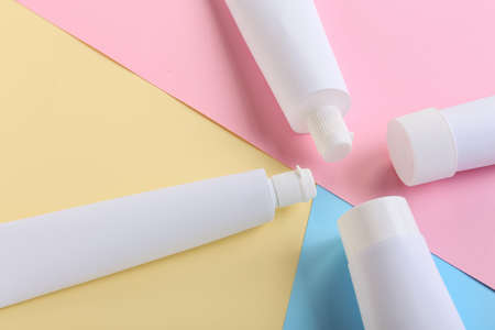 Tubes with toothpaste on color background