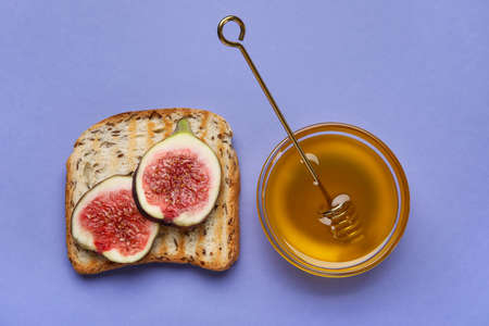 Toast with ripe figs and honey on color backgroundの写真素材