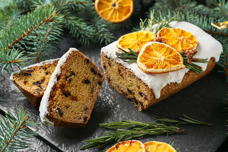 Tasty Christmas stollen with fir branches on dark background