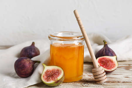 Glass jar with honey and ripe figs on tableの写真素材