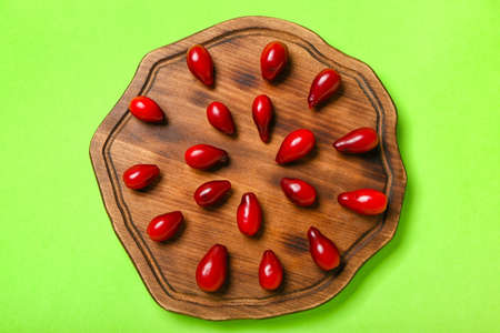Board with ripe dogwood berries on color background