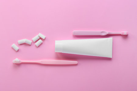 Tube with tooth paste, brushes and tasty chewing gums on pink backgroundの写真素材