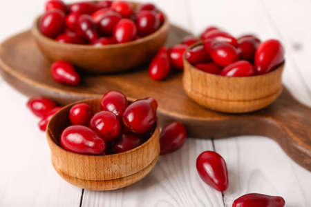 Bowls with ripe dogwood berries on light wooden background, closeupの写真素材