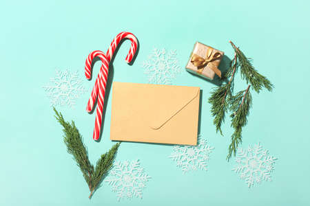 Christmas composition with envelope, candy canes and gift box on color backgroundの写真素材