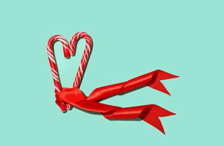 Heart made of candy canes and ribbon on color backgroundの写真素材