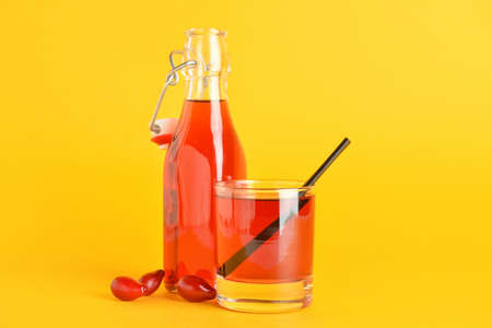 Glass and bottle of healthy dogwood berry drink on color backgroundの写真素材