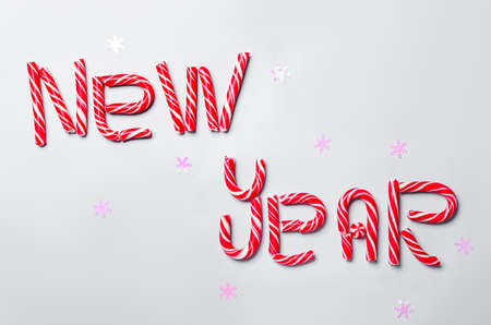 Text NEW YEAR made of candy canes on white background