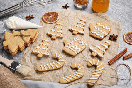 Parchment with Christmas gingerbread cookies and spices on gray background