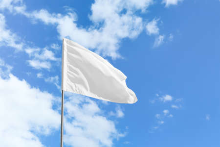 Waving white flag against blue sky