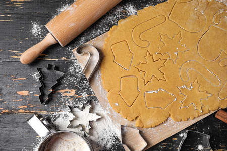 Process of making Christmas gingerbread cookies on dark wooden background