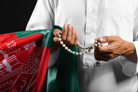 Muslim man with flag of Afghanistan and tasbih on dark background, closeupの写真素材