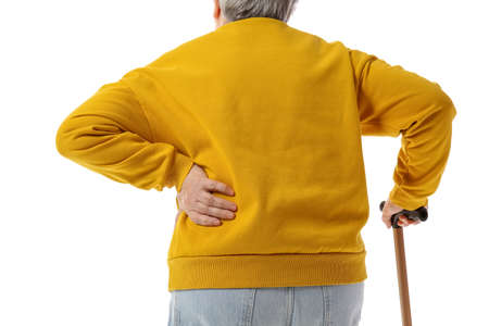 Senior woman with walking stick suffering from back pain on white background