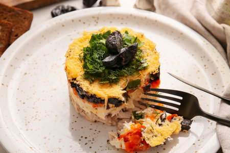 Delicious layered salad with prunes and cutlery in plate on table, closeup