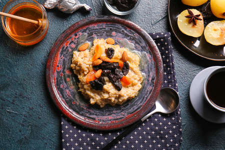 Plate with sweet oatmeal, prunes, dried apricots and almond nuts on dark tableの写真素材