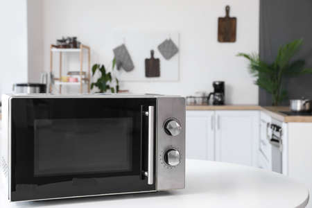 Microwave oven on white table in light kitchenの写真素材