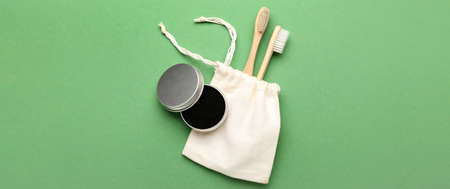 Jar with activated charcoal tooth powder and brushes on green background with space for text, top viewの写真素材