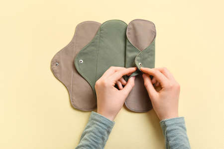 Female hands with reusable menstrual pads on yellow backgroundの写真素材